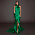 Woman wearing a green evening gown with a high slit on a dark background