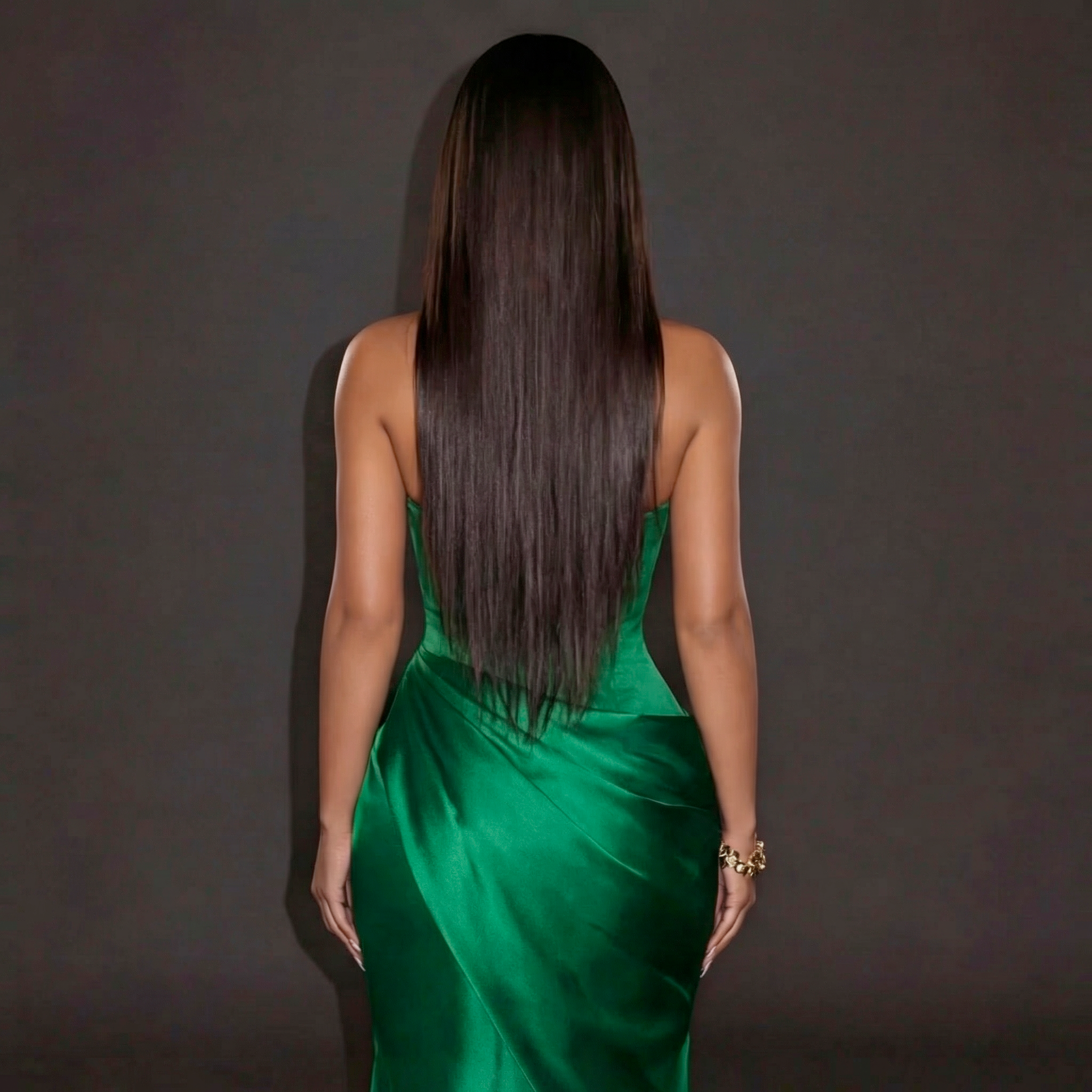 Woman in a green dress with long hair against a dark background