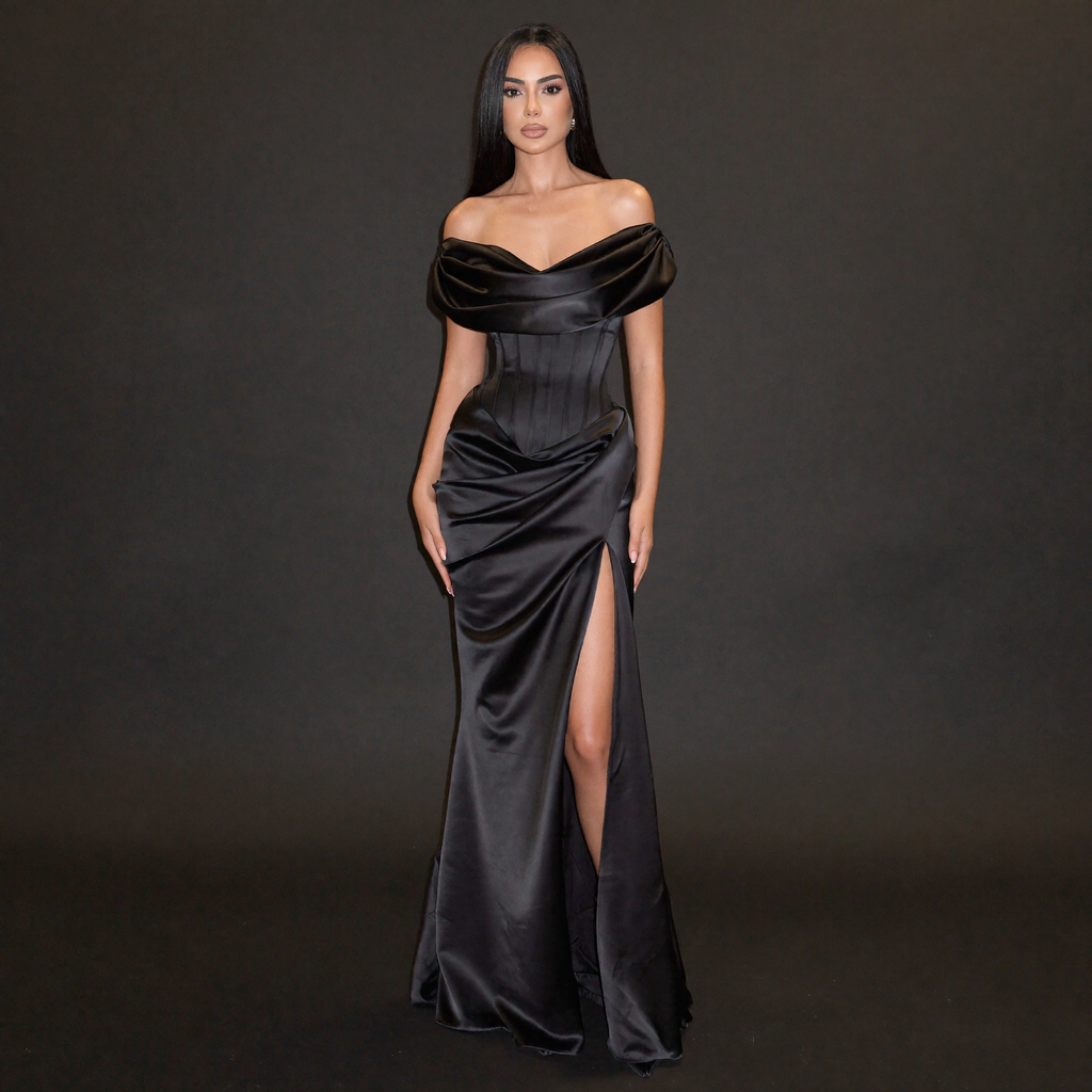 Woman wearing a black off-shoulder gown with a slit on a dark background
