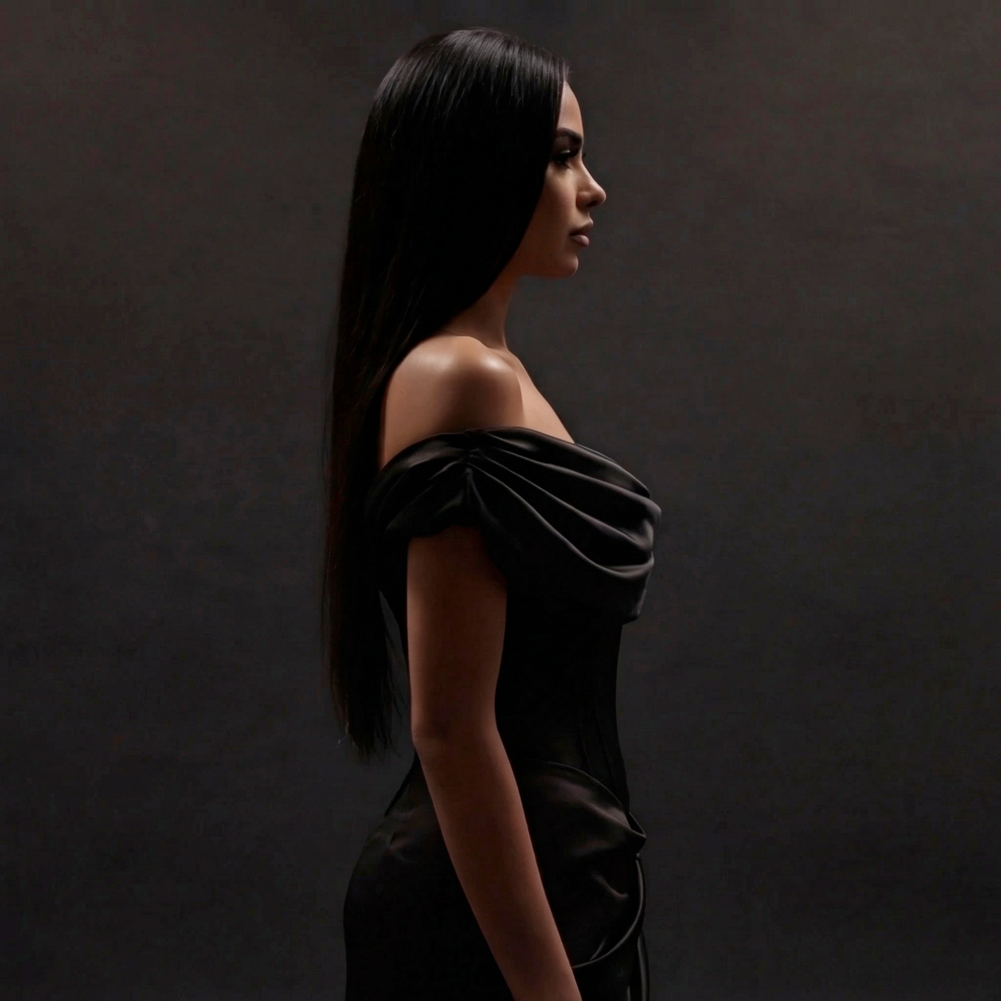 Woman in a black off-shoulder dress against a dark background
