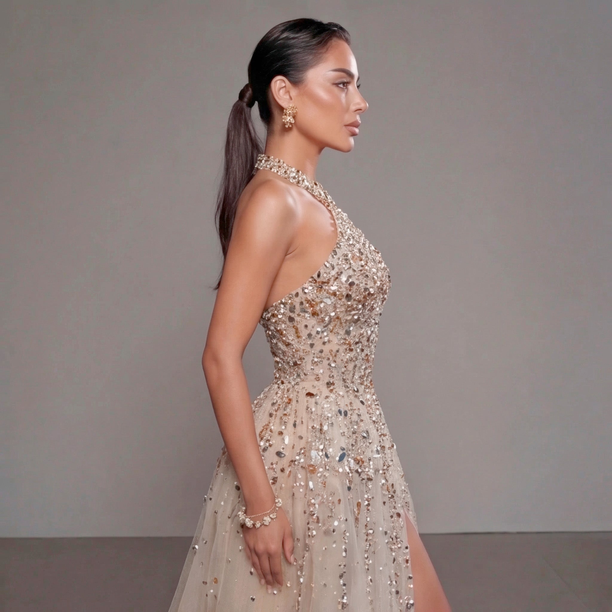 Woman wearing a sparkling evening gown against a neutral background