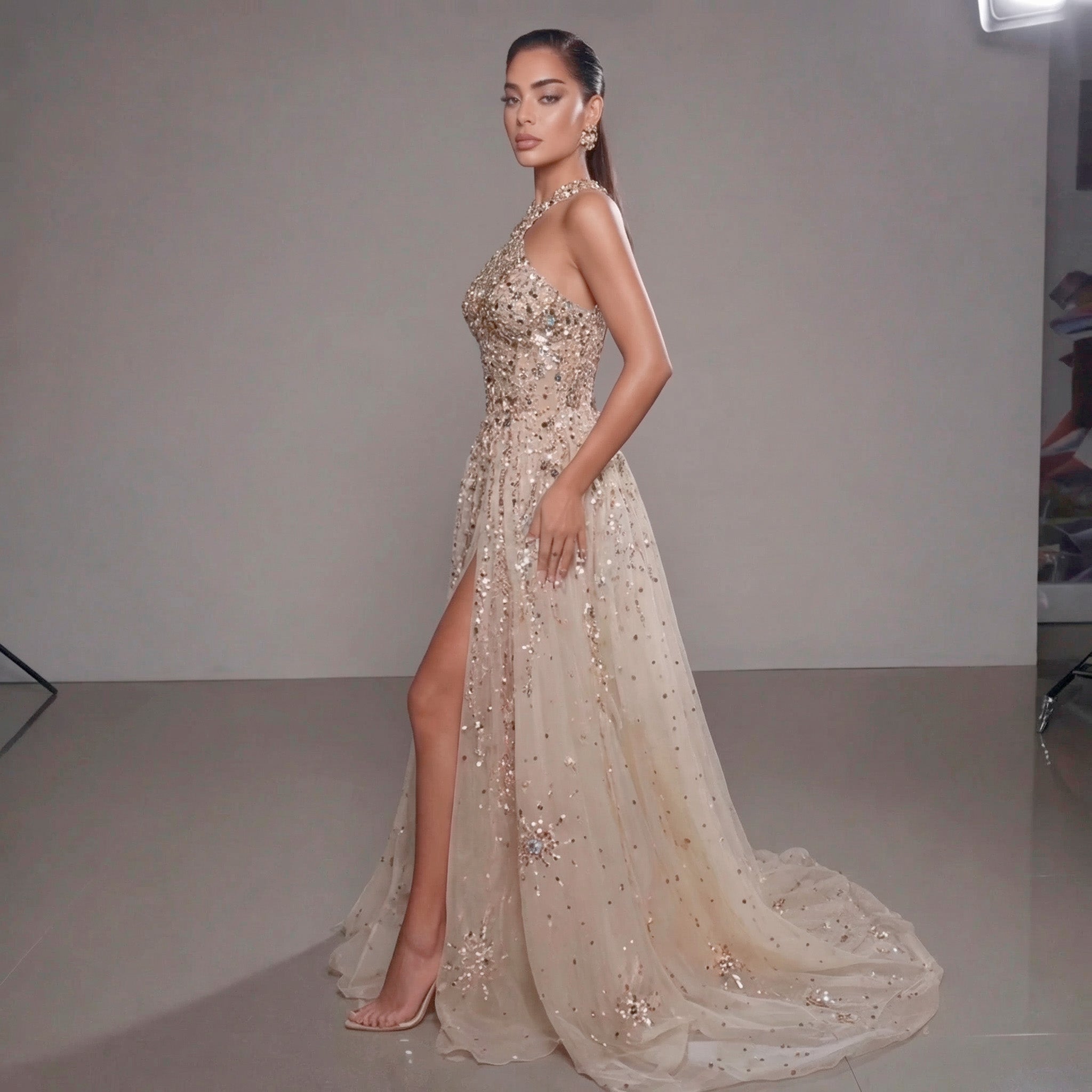 Woman wearing a sparkling evening gown with a high slit on a plain background