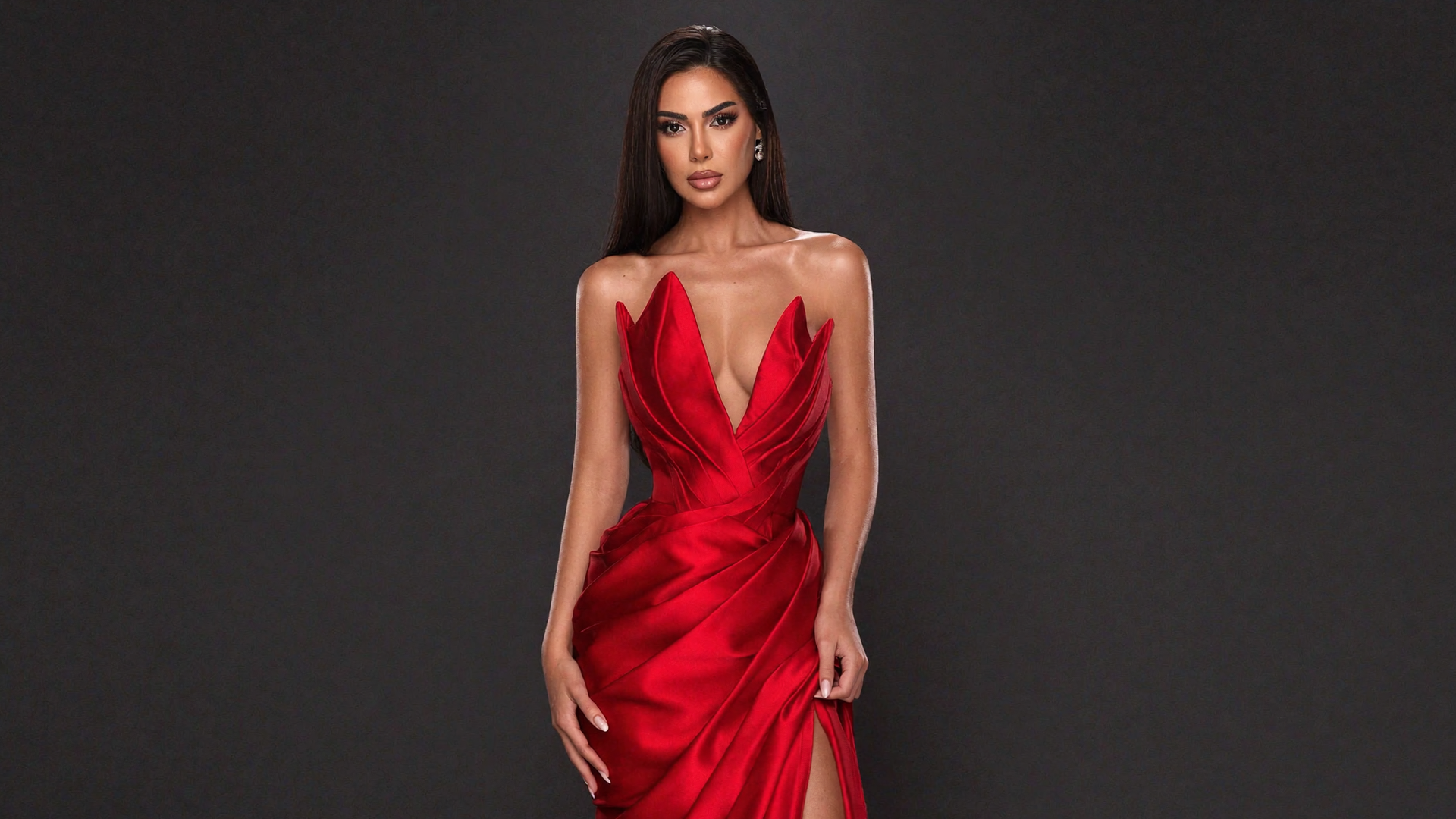 Woman wearing a red dress with a deep neckline on a black background